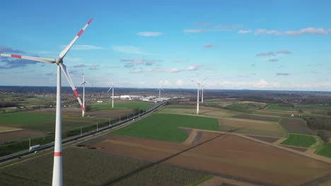 aerial of wind turbine farm in fields, high way crosses the landscape