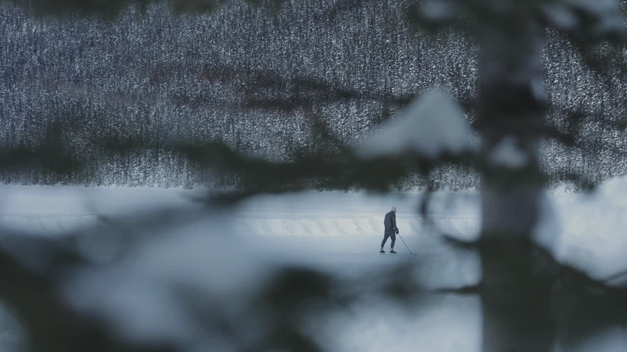 Man Ice Skating on a Frozen Lake in a Snowy Forest