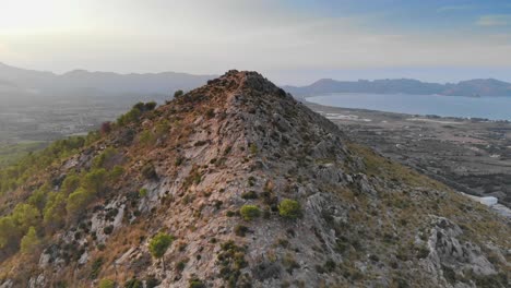 aerial drone approaching a natural mountain peak with ocean in the background, spain