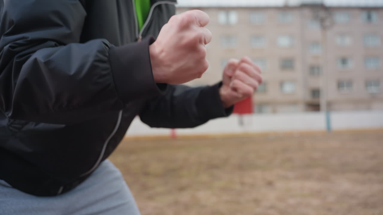 동네 축구장에서 운동 준비를 하는 남성, 운동 활동 전에 손을 준비하는 운동선수의 클로즈업, 경기 전에 동네 축구장에서 워밍업과 그립 조정을 연습하는 개인