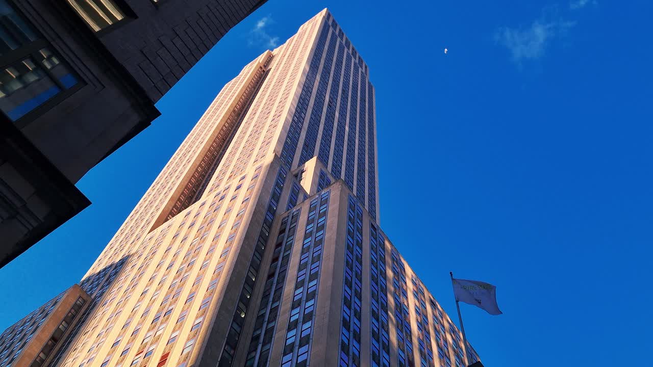 view of the blue sky of new york with 3 buildings and some clouds.