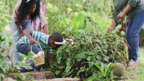 Animation-of-happy-african-american-family-searching-for-easter-eggs-in-garden