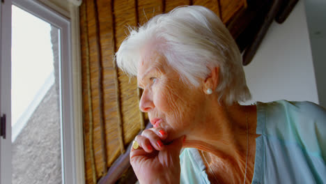 Side-view-of-thoughtful-old-Caucasian-senior-woman-sitting-near-window-at-home-4k