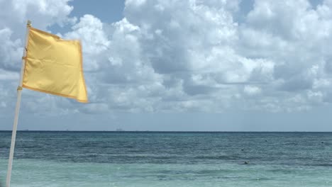 gelbe flagge weht im wind, mit blick auf das meer und den bewölkten himmel