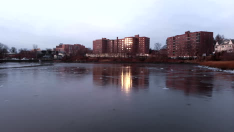 a shot moving across ice looking toward an apartment building with the sun reflecting off the windows