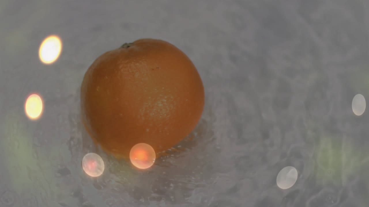 Ripples intensifying under floating orange fruit causing rotating and drifting bokeh flickering