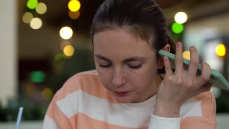 pretty woman eating salad and listens to a voice message on the phone. lunch at the food court of shopping mall.