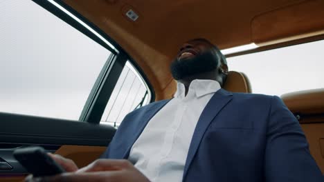 african businessman looking smartphone at car. afro man holding phone at vehicle