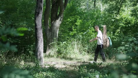 young man walking with guitar on street near forest