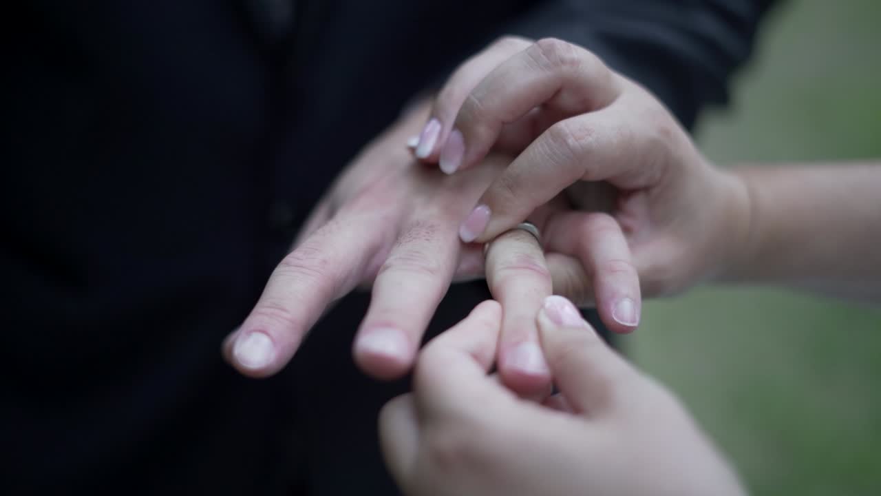 Emotional moment as a fiancé delicately touches his future bride's hand, revealing a stunning diamond ring and a lifetime of promises.