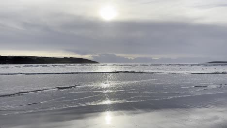 Olas-Plateadas-En-Una-Playa-De-Arena-En-Invierno-Con-Sol-Brillante-Luz-Plateada-En-Irlanda