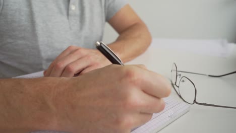 man writing on a desk to his notepad