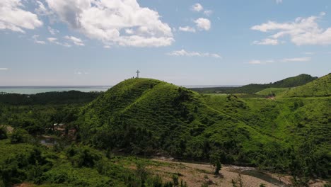 acercándose a una cruz situada en la ladera de una colina junto al océano