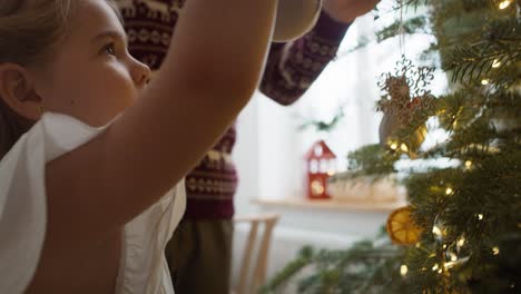 niña con papá decorando el árbol de navidad