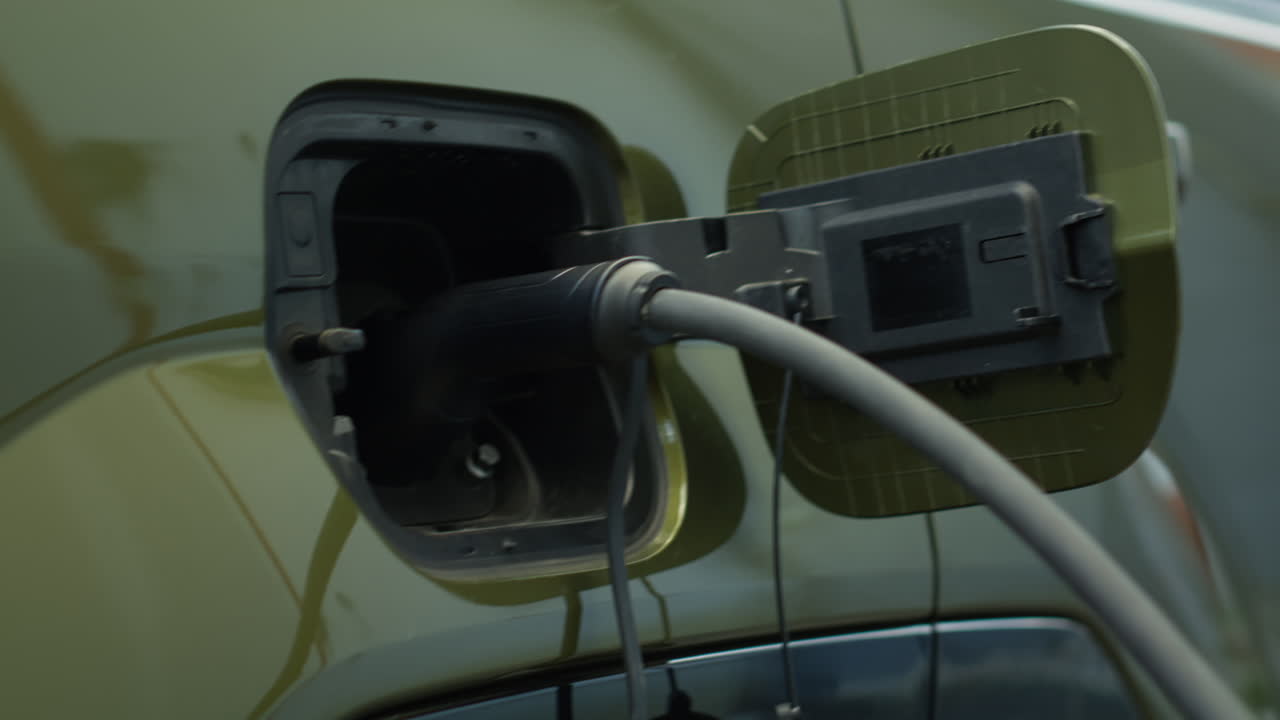 Close Up Of Ev Vehicle Being Left To Charge In Parking Lot