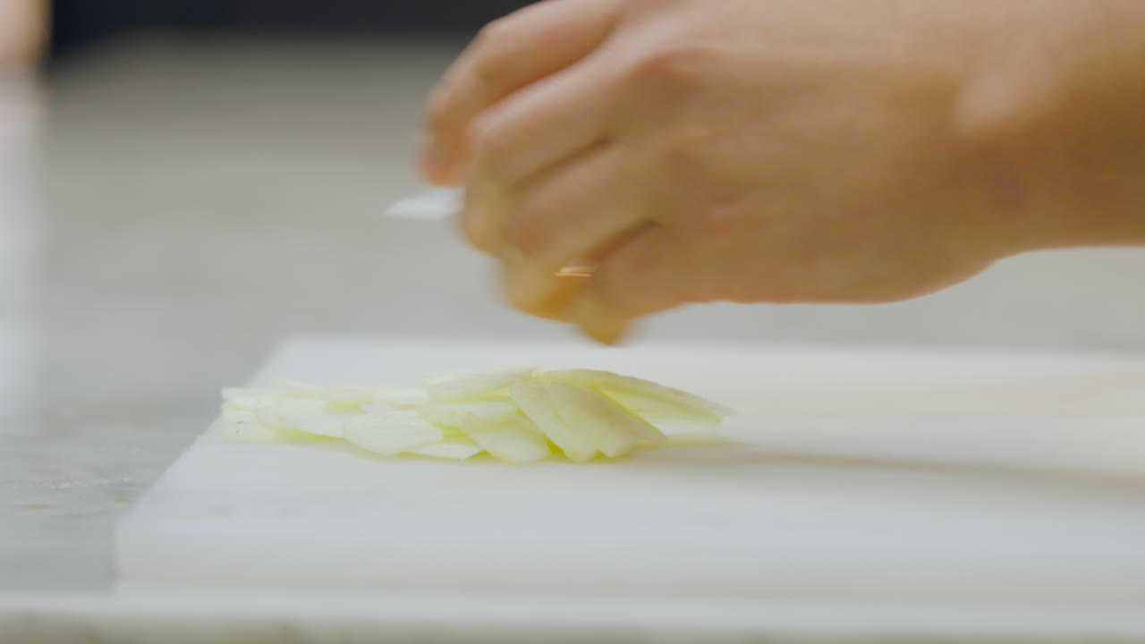 Close-up of a chef using a knife to separate and remove freshly cut apple slices on a chopping board