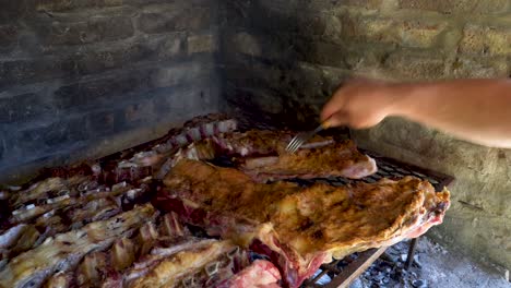 Männerhände-Bewegen-Sich-Um-Rindfleischstücke-In-Argentinischem-Asado,-Um-Sie-Gleichmäßig-Zu-Garen