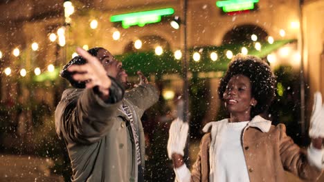 vista de cerca de una alegre pareja afroamericana jugando con la nieve en la calle en navidad