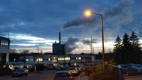 power plant in industrial area in front of blue dusk sky producing a huge vapor cloud