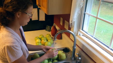 woman washing apples for applesauce in kitchen sink