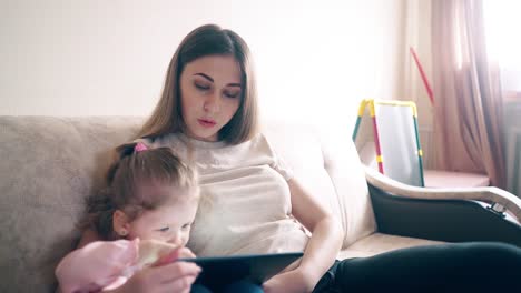 cu young attractive mother and sweet daughter are sitting on the couch