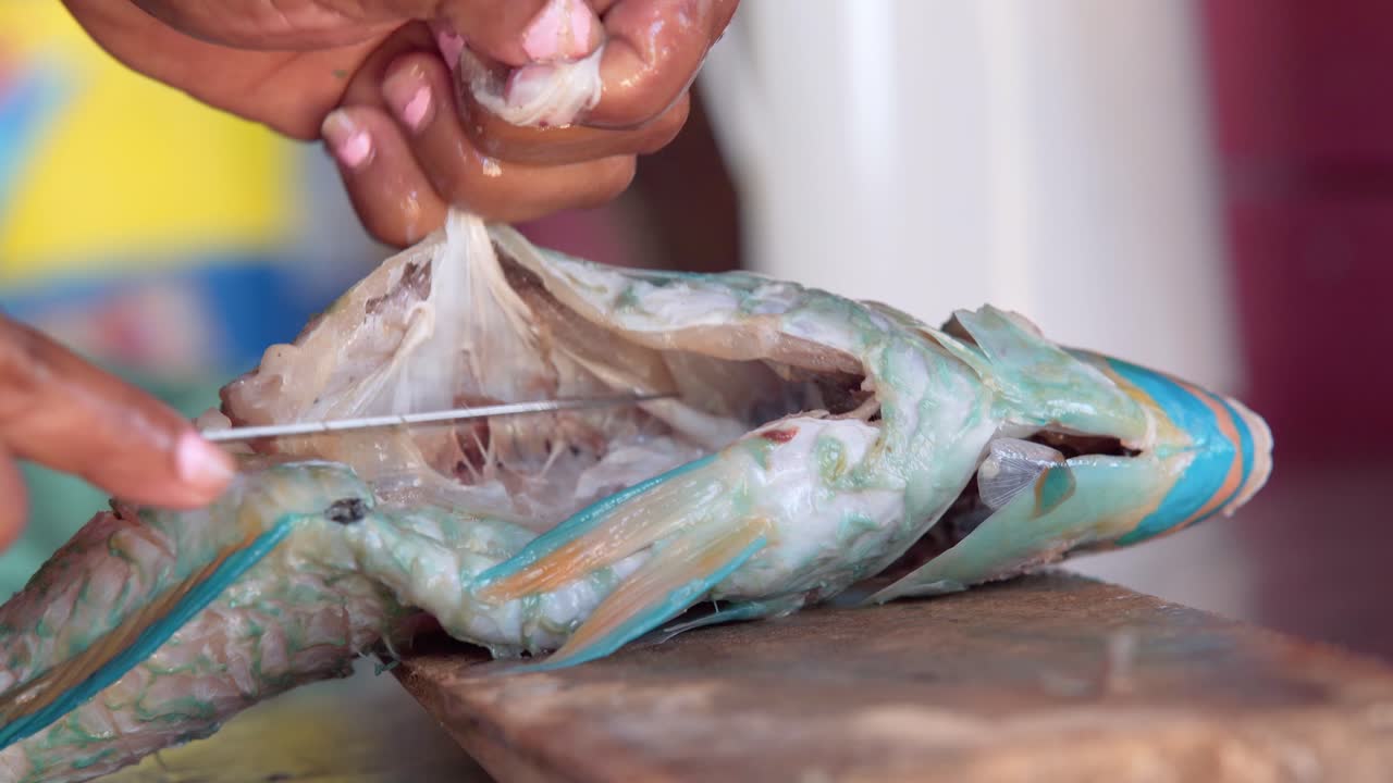 여성은 도미니카 공화국의 겸손한 마을에서 건강한 음식을 만들기 위해 생선을 자른다