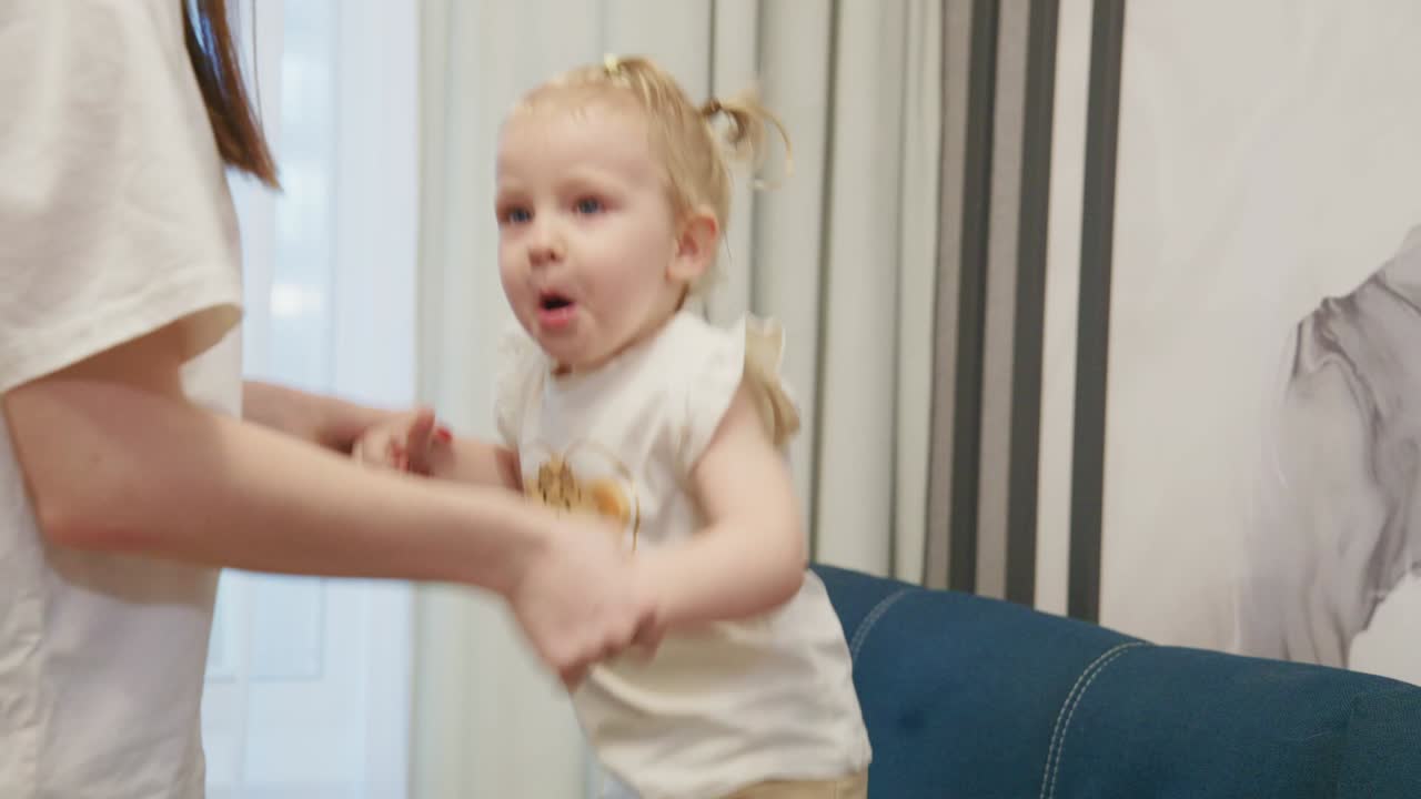 Happy Baby Girl Jumping with Mother Holding Hands
