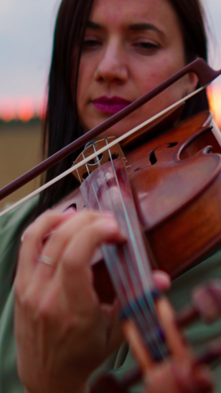 Woman Playing Violin in a Field at Sunset