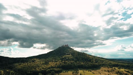 drone view tilting up of the hohenzollern castle atop hohenzollern mountain during daylight and the beautiful countryside in zollernalbkreis, germany