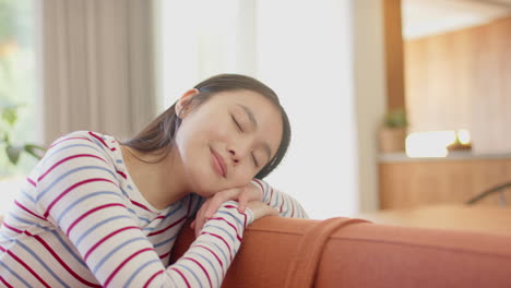smiling asian teenage girl resting on couch, enjoying peaceful moment at home