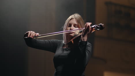 Una-Mujer-Emocional-Está-Tocando-El-Violín-En-Un-Cuarto-Oscuro.-Retrato-De-Una-Violinista-Con-Violín.