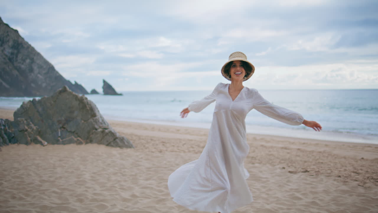 feliz viajero girando playa en un día nublado de verano. mujer despreocupada disfrutando