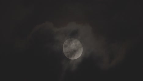 a full moon in a sky with clouds moving