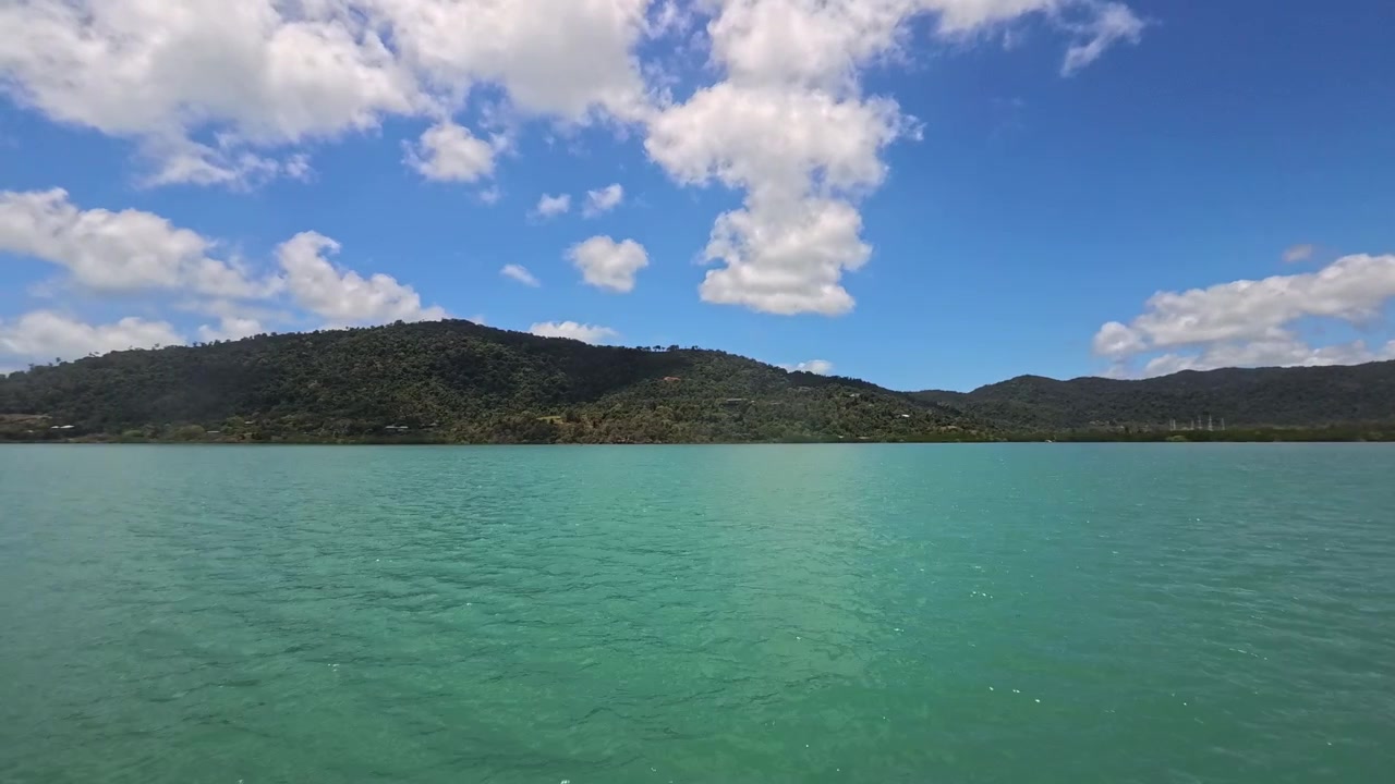 Vue panoramique sur les eaux turquoise de l'océan et les collines verdoyantes sous un ciel bleu