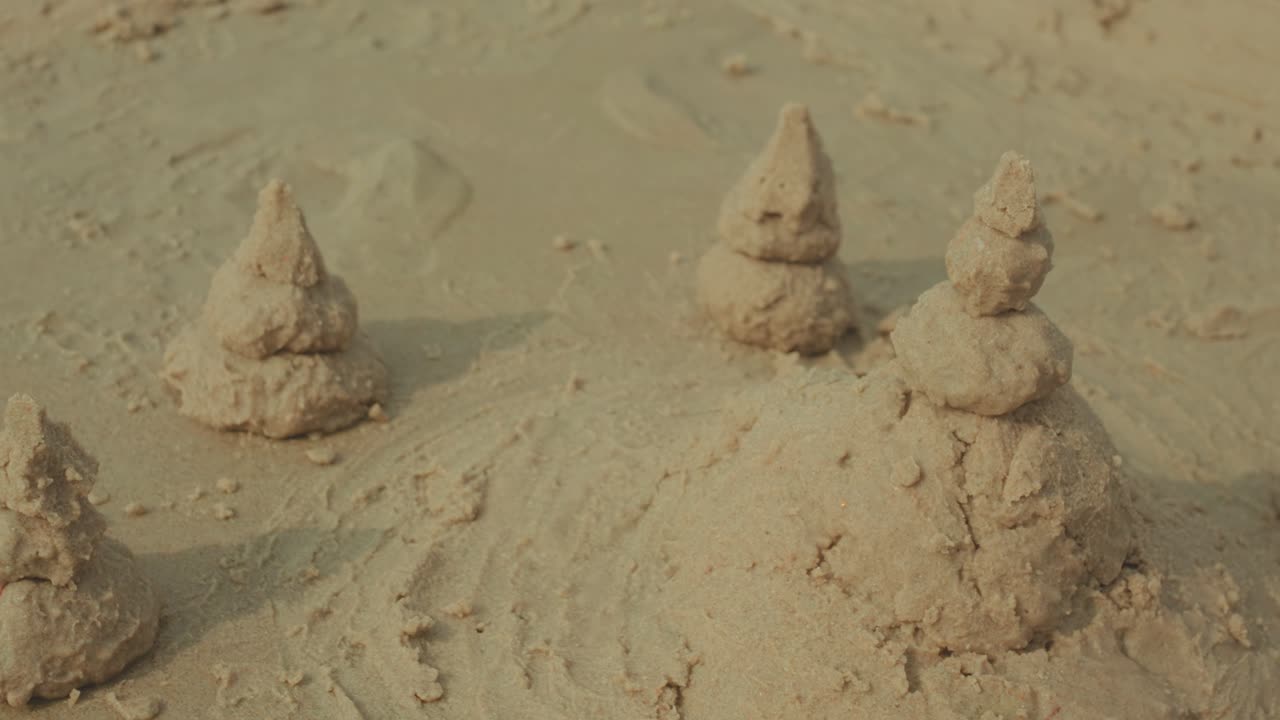 Pequenas torres de areia dispostas na superfície da praia, cena de textura costeira criativa e simples