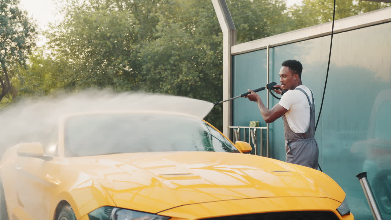 남자가 야외 세탁소에서 노란색 스포츠카를 고 있다