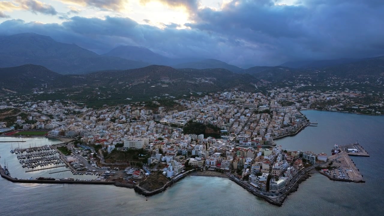 Vista aérea de drone da cidade costeira e seu porto sob um céu nublado, Agios Nikolaos, Grécia