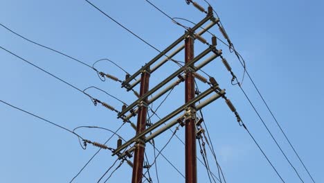 static shot of a power transmission tower against a clear blue sky. the tower is constructed from metal and features multiple wires and insulators