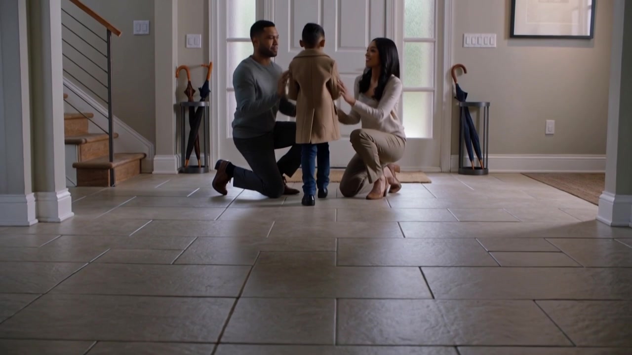 Smoothing child's beige coat, smart parents kneeling guiding child opening foyer door to go outside