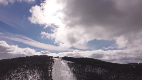 drone flying over ski resort with beautiful clouds and sun