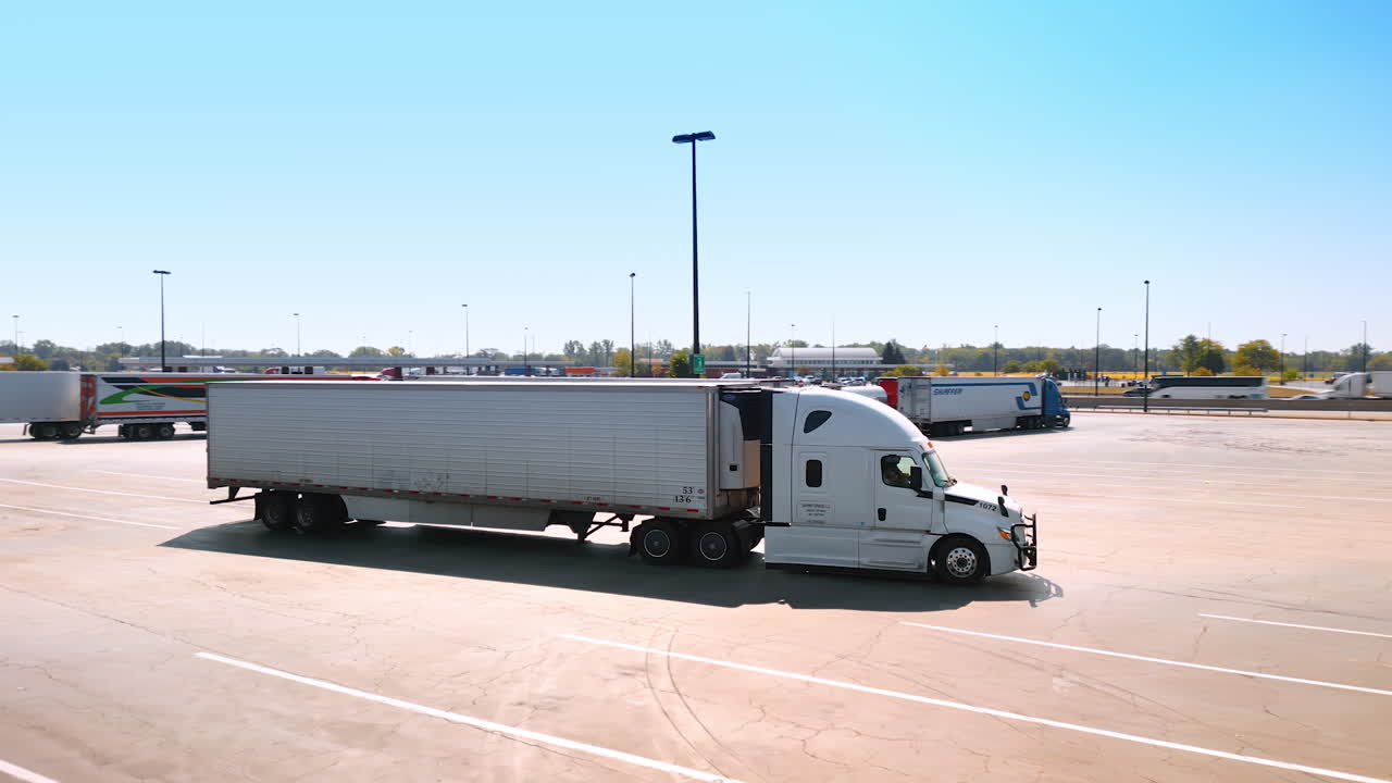 Chicago, USA, 29 June 2025: Modern truck setting off from the car park with another lorries. Highway and gas station at backdrop
