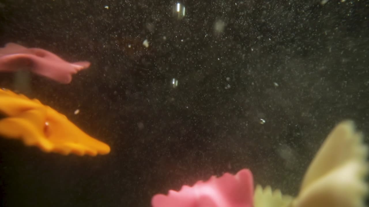 슬로우 모션으로 물 속으로 떨어지는 다채로운 파팔레 파스타.