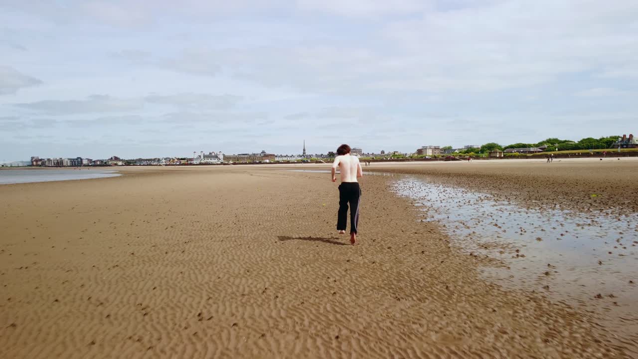 휴식을 취하기 위해 멈추기 전까지 모래 해변에서 조 ⁇ 하는 젊은 성인 남성