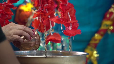 worshipper pouring water over the shivling shiv ji murti in hindu temple