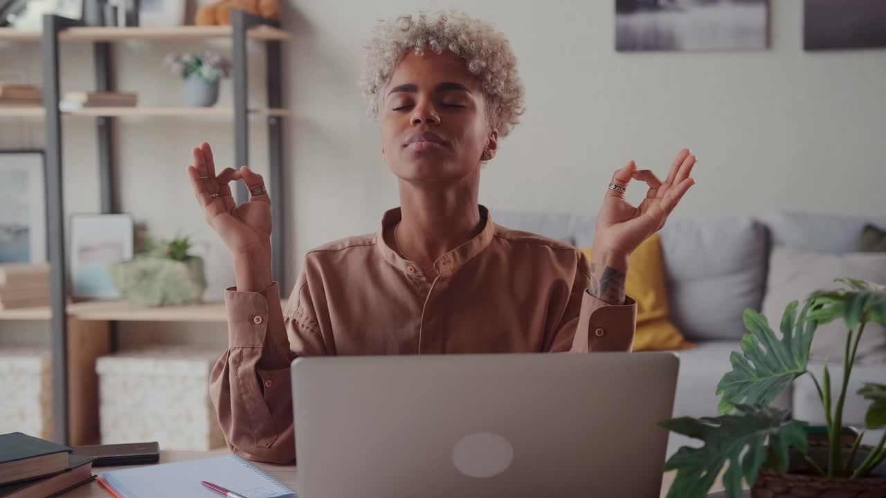 African american woman near laptop practicing meditation at home office desk