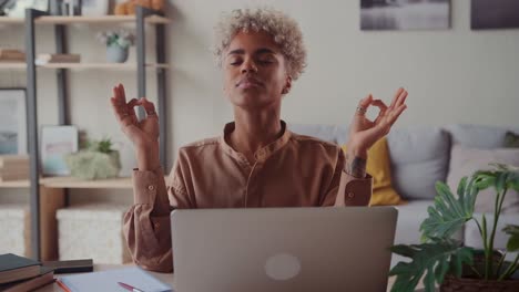 african american woman near laptop practicing meditation at home office desk