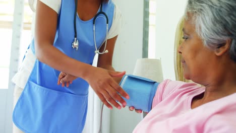 Female-doctor-measuring-blood-pressure-of-senior-woman-in-bedroom-4k