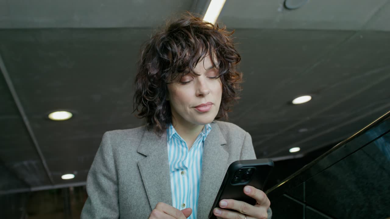 mujer de negocios usando un teléfono inteligente en una escalera mecánica