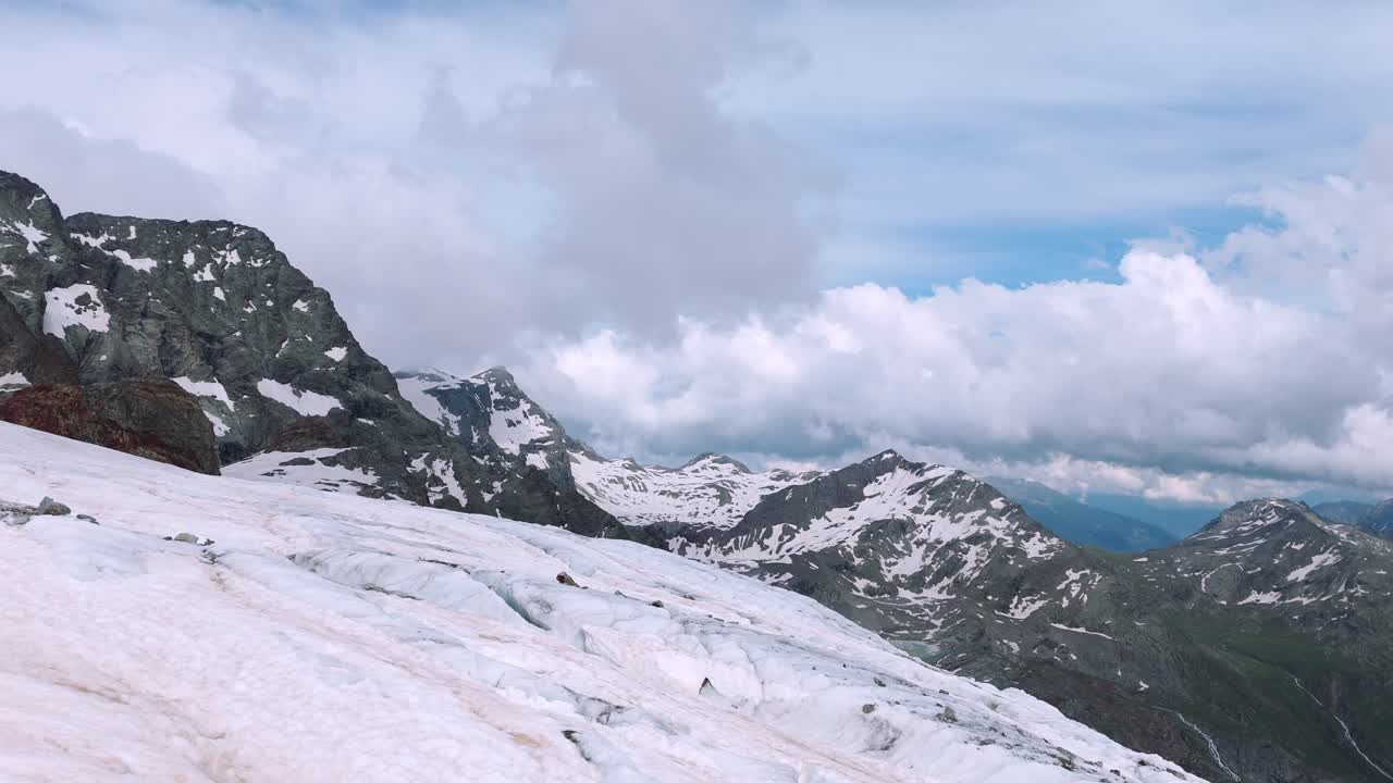 Drone footage of Fellaria Glacier in Valmalenco, Alps, capturing breathtaking snow-covered peaks and rugged mountain terrain. A tilt-down camera movement reveals stunning glacial textures