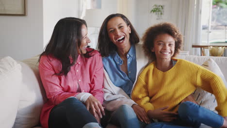 three generation african american female family group sitting on sofa laughing together